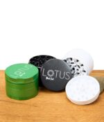 Black Leaf Lotus Grinder 63mm in Grün, Schwarz und Weiß, teilweise geöffnet und gestapelt auf Holztisch