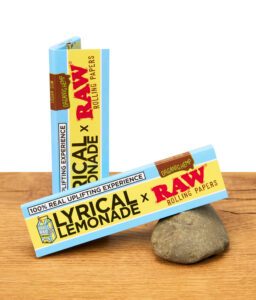 RAW x Lyrical Lemonade Rolling Papers mit veganem Gummi und organischem Hanf auf Holztisch, Verpackung im Fokus.