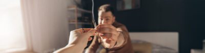 Joint wird weitergereicht, während ein Mann im Hintergrund hustet, weil Cannabis kratzt beim Rauchen