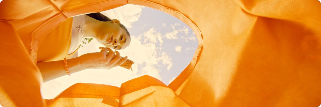 Der orangene VEAZY Vaporizer in orangener Tasche im gleichen Farbstil mit Blick auf den Himmel.