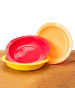 Drei Black Leaf Silikonteller in Gelb, Rot und Orange, ineinander gestapelt, ideal als hitzebeständige Zubehör-Unterlage, auf rustikalem Holztisch.