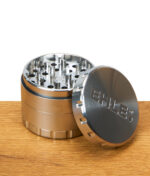 Geöffneter EHLE Grinder aus Edelstahl, Mahlzähne und Deckel mit Logo auf Holztisch sichtbar.