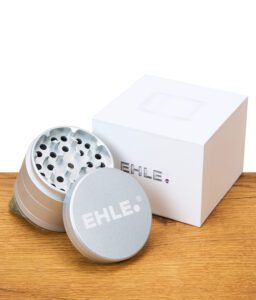 Geöffneter EHLE Keramik Grinder mit weißer Verpackung und sichtbarer Mahleinheit auf Holztisch.