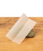 Ein einzelnes ungebleichtes RAW Black Classic Rolling Paper 1 1/4 Size auf einem Stein und Holzhintergrund.