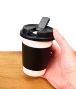 Hand hält schwarz weißen Puffco Cupsy, eine Bong in Kaffeebecher Design