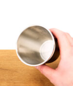 Hand hält Edelstahl becher des Puffco Cupsy for weißem Hintergrund
