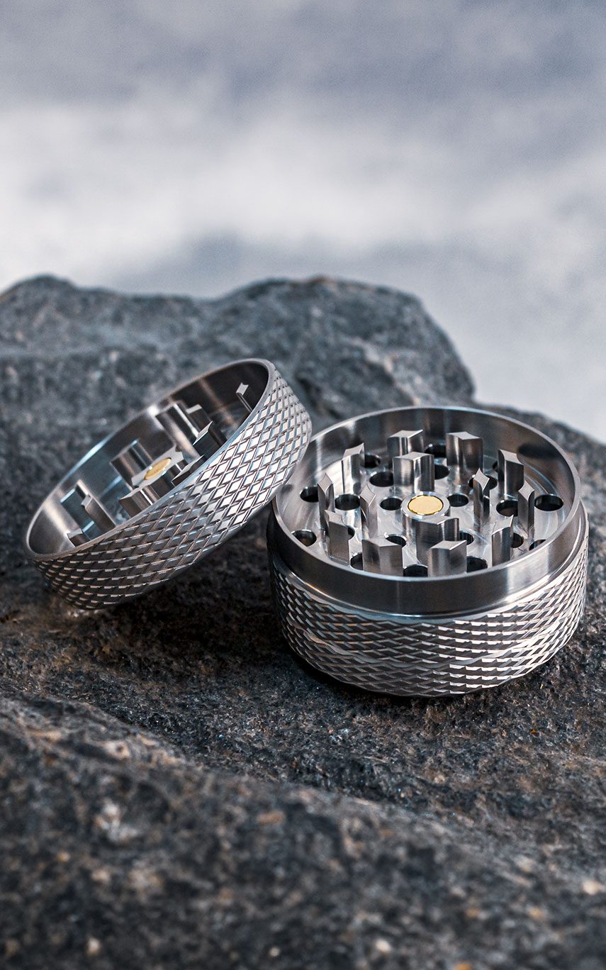 Das Bild zeigt den geöffneten GRIPO Premium Grinder 55 mit Blick auf das Mahlwerk auf einem Naturstein vor einem grauen Hintergrund platziert.