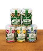 Fünf Purize Gläser mit Aktivkohlefiltern in verschiedenen Farben stehen in zwei Reihen auf einer Holzoberfläche vor weißem Hintergrund, Vordergrund mit grünen Etiketten „XTRA Slim Size 100“.