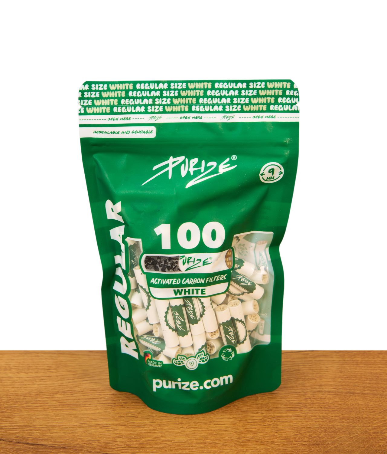 purize-regular-size-100er-pack-white-jpg Grüne Purize 100er Pack Regular Size Verpackung mit weißen Aktivkohlefiltern steht aufrecht auf einer Holzoberfläche vor weißem Hintergrund, Sichtfenster zeigt cremefarbene Filter mit grünem Logo.