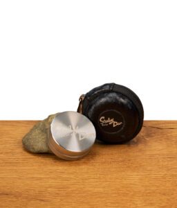 Kleiner Steely Dan Edelstahl Grinder 39mm lehnend an einem Stein neben schwarzem Hardcase