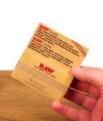 RAW Classic Double Wide Papers Heftchen in der Hand gehalten zur Veranschaulichung der doppelten Breite für breitere Selbstgedrehte.