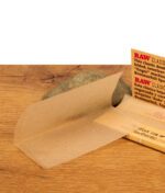 Einzelnes, entnommenes RAW Classic Double Wide Paper mit charakteristischem Criss-Cross-Wasserzeichen vor einem Dekostein.