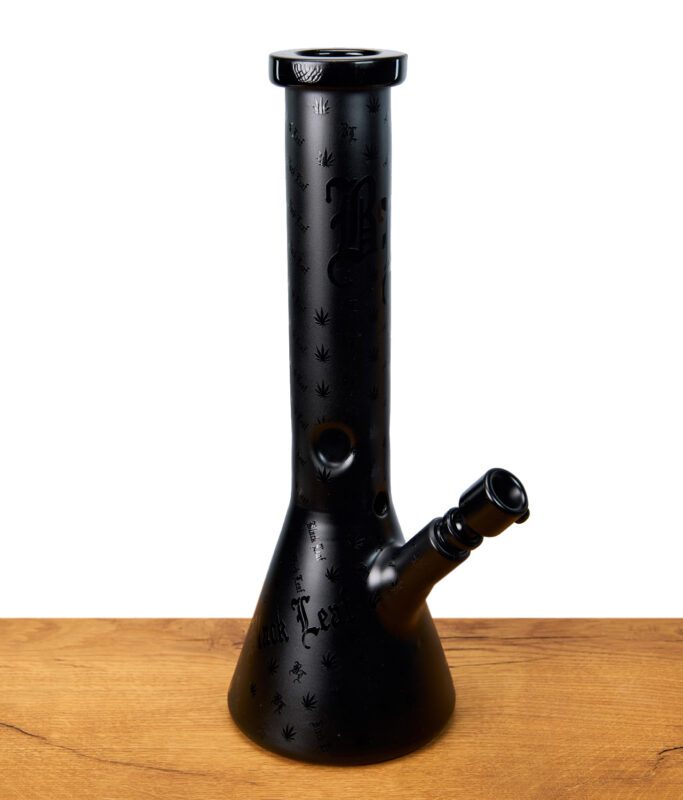 Schwarze Black Leaf Beakerbong mit eingravierten Hanfblättern und Schriftzug, seitliche Ansicht auf Holztisch.