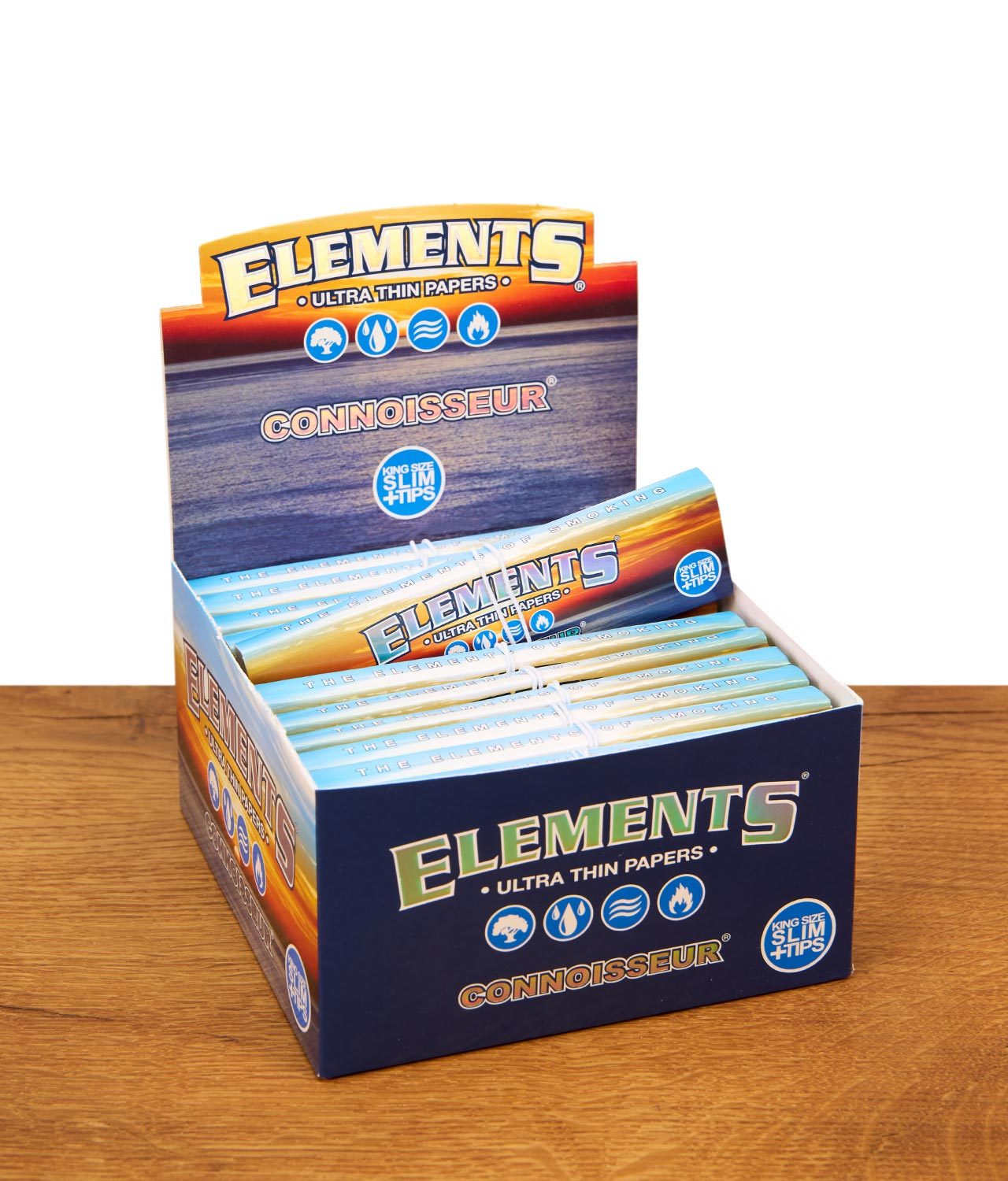 elements-connoisseur-ultra-thin-papers-mit-tips-24er-box-jpg Geschlossene 24er Box der Elements Connoisseur Ultra Thin Papers mit farbenfrohem Sonnenuntergang-Design auf einer Holzoberfläche.