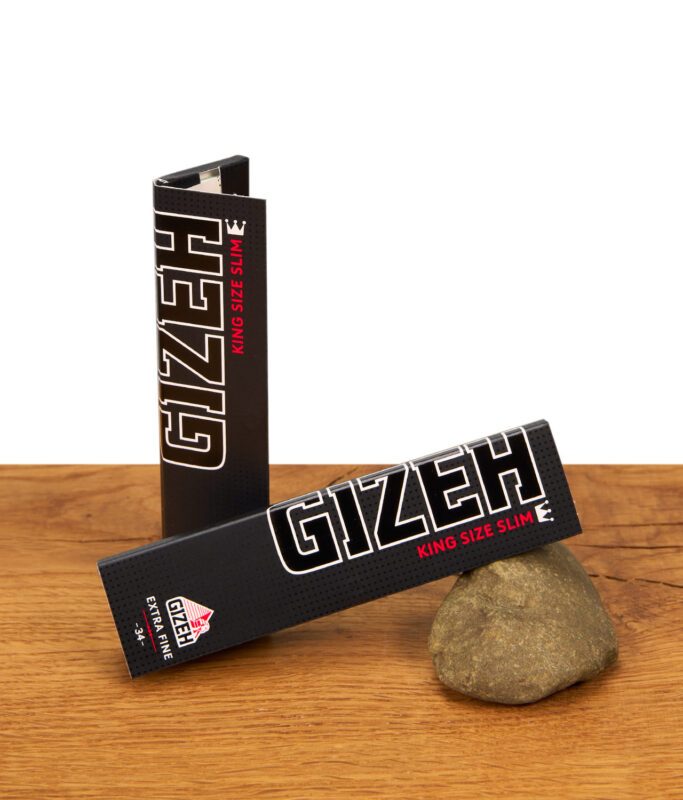Zwei Packungen Gizeh Black King Size Slim Papers mit Magnetverschluss auf einer Holzoberfläche mit Naturstein-Deko.