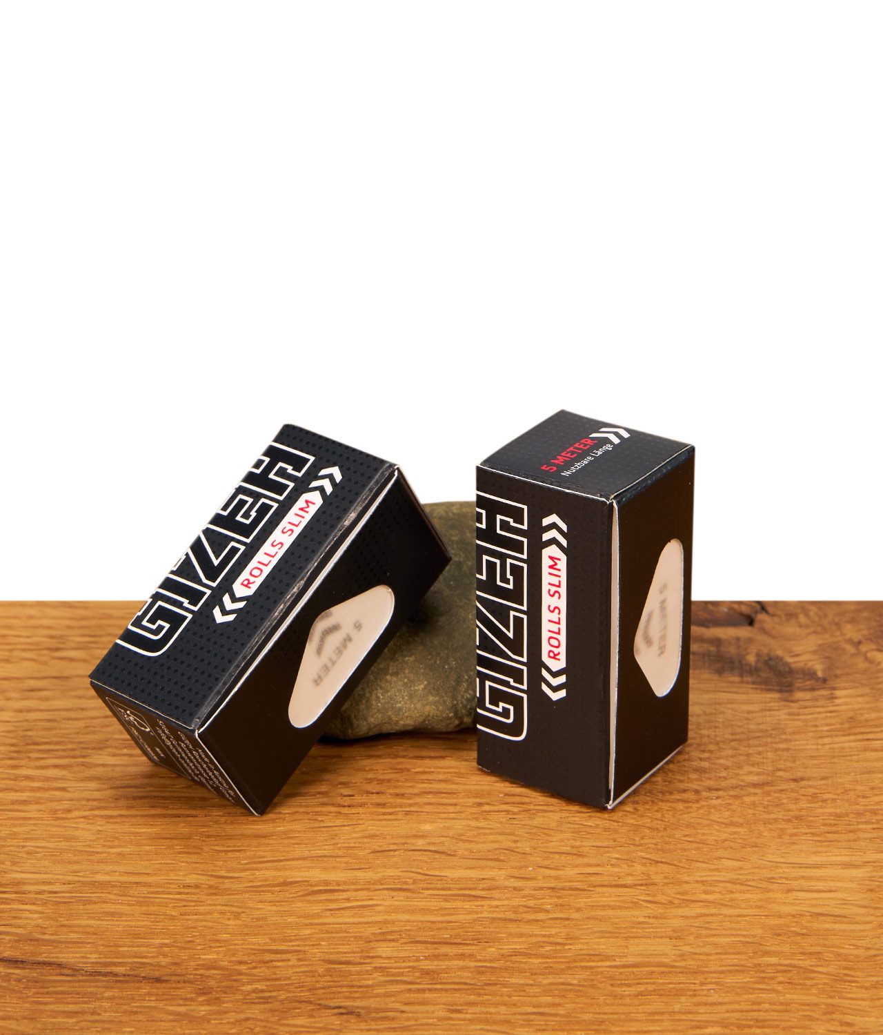 gizeh-black-extra-fine-slim-size-endlospaper-jpg Zwei schwarze Gizeh Black Rolls Slim Packungen mit 5 Meter extra feinem Endlospapier auf einer Holzoberfläche vor einem Naturstein.
