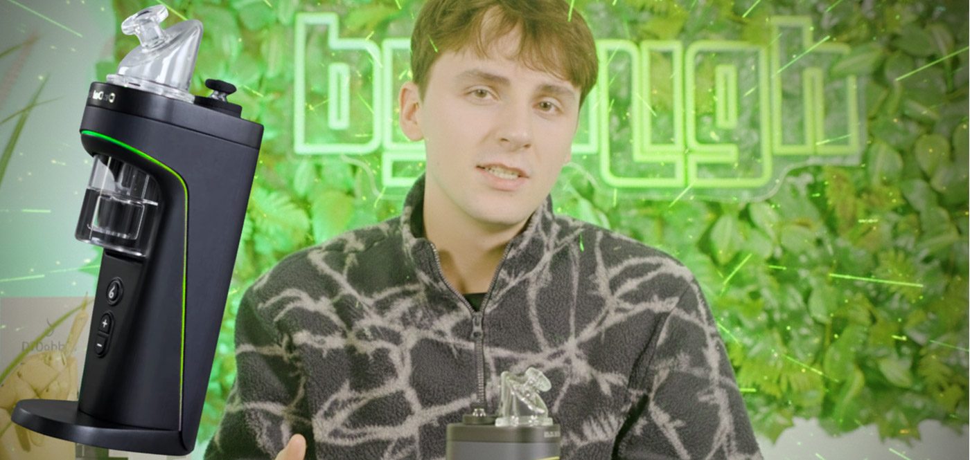 Dr. Dabber Switch 2 im Test: Ein junger Mann im gemusterten Fleece steht vor einer grünen Pflanzenwand mit einem hellgrün leuchtenden „buyhigh“ Neonschild, während links im Vordergrund der Vaporizer mit aktiviertem LED-Streifen groß eingeblendet ist.