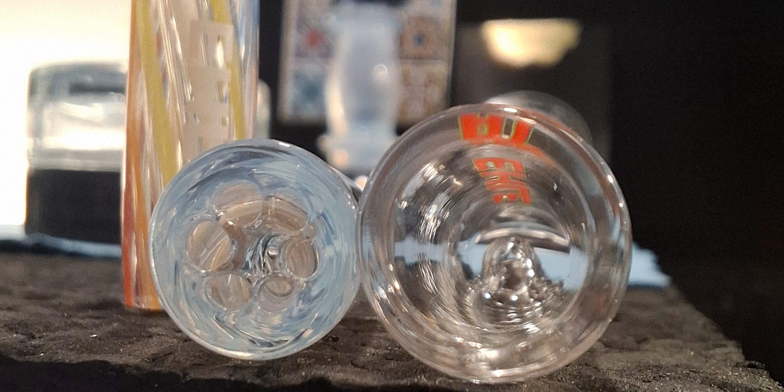 Nahaufnahme zweier Glasfilter für Joints aus klarem Borosilikatglas mit integriertem Sechs-Loch-Sieb und Aufsteck-Glasfilter im Test.
