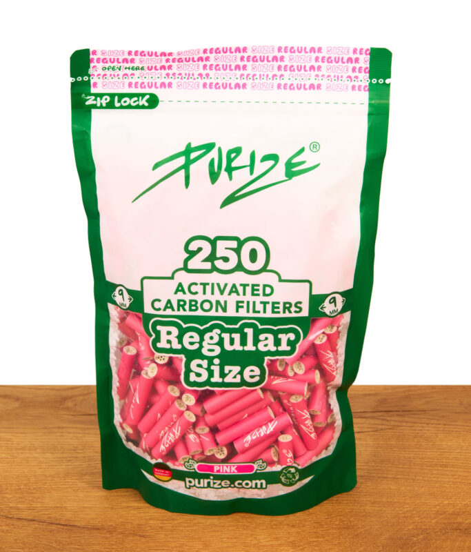 PURIZE Regular Size 250er Pack Aktivkohlefilter (9mm) in Pink. Frontalansicht des Standbodenbeutels mit Sichtfenster auf Holz.