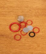Ausgepacktes Tinymight Ersatzteilset mit diversen roten und schwarzen O-Ringen sowie feinmaschigen Edelstahlsieben auf einer Holzplatte.