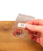 Hand hält das verpackte Tinymight Ersatzteilset, das rote Silikon-Dichtungsringe und feine Edelstahlsiebe enthält.