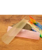 Ein entnommenes, ultradünnes Elements Prism Paper liegt über einem Stein neben dem geöffneten Heftchen.