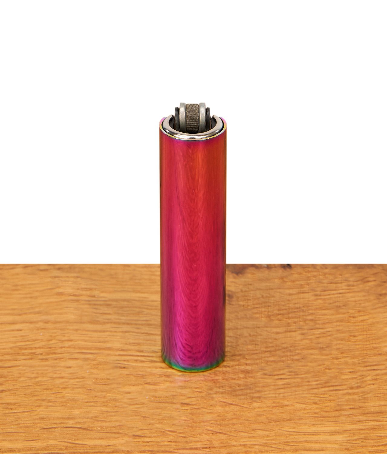 clipper-feuerzeug-micro-metal-rainbow-icy-colors-jpg Frontale Ansicht des nachfüllbaren Metal Clipper Feuerzeugs Rainbow mit markanter vertikaler Iridiscent-Maserung, zentriert auf einer Holzoberfläche.
