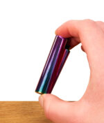 Nahaufnahme einer Hand, die das nachfüllbare Metal Clipper Feuerzeug Rainbow zwischen Daumen und Zeigefinger hält, wobei die Iridiscent-Oberfläche violett-blau schimmert.