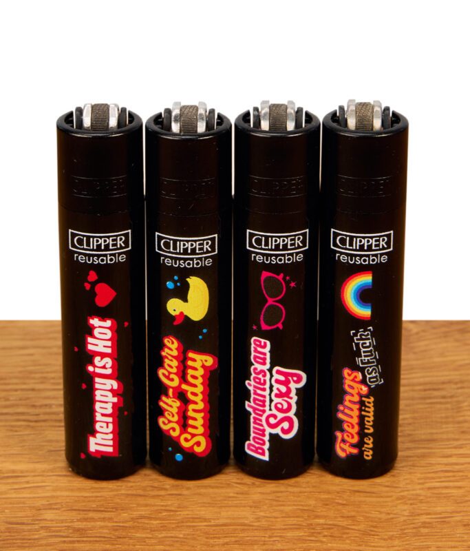 Set aus vier nachfüllbaren Clipper Feuerzeugen der Mental Health Kollektion auf Holz, mit Sprüchen: "Therapy is Hot", "Self-Care Sunday", "Boundaries are Sexy", "Feelings are Valid".