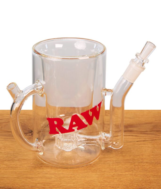 RAW Wake Up & Bake Up Mug aus Borosilikatglas mit integriertem Perkolator-System und rotem Logo auf hellem Holzgrund.