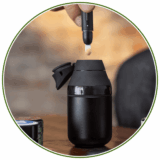 Das Bild zeigt ein Vaporizer für Extrakte. Dabbing Kategorie auf buyhigh mit lifestyle bild eines schwarzen Vaporizers und Hand welche mit einem Tool ein Extrakt fallen lässt.
