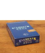 Geschlossene 25er Vorratsbox der Elements Phantom Papers im 1 1/4 Size Format mit holografischem Logo auf Holzgrund.