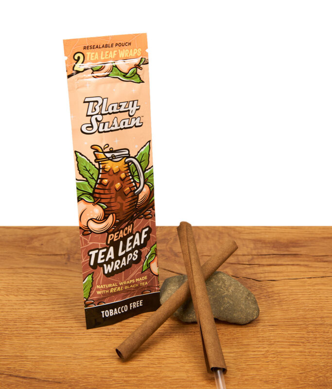 Blazy Susan Tea Leaf Wraps Peach (2er Pack) neben zwei tabakfreien Wraps aus echtem Schwarztee auf einem Stein.