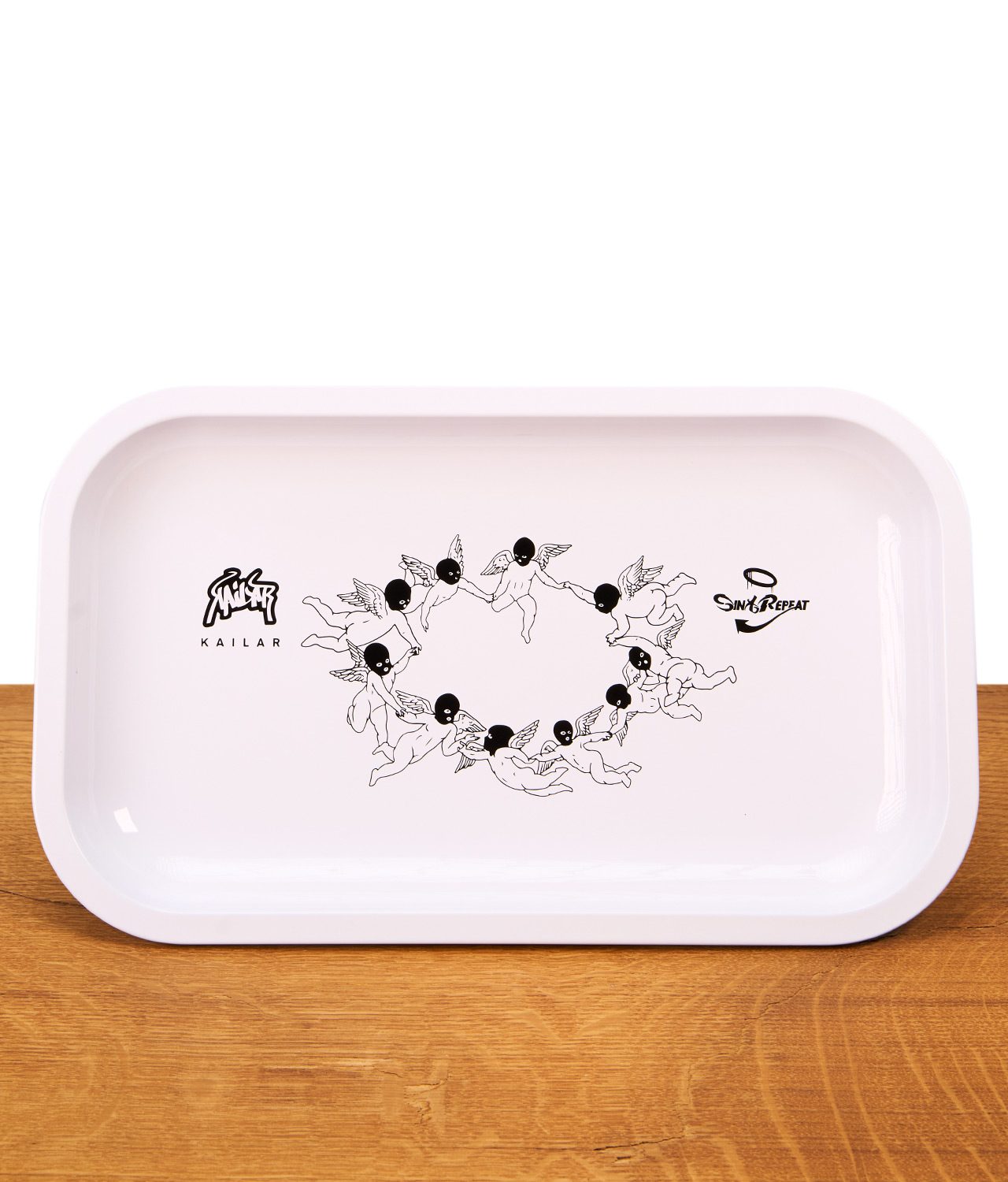 kailar-rolling-tray-sin-and-repeat-jpg Das weiße Kailar Rolling Tray "Sin & Repeat" aus Metall in der Frontalansicht mit dem zentralen Motiv tanzender Engel mit Sturmhauben.