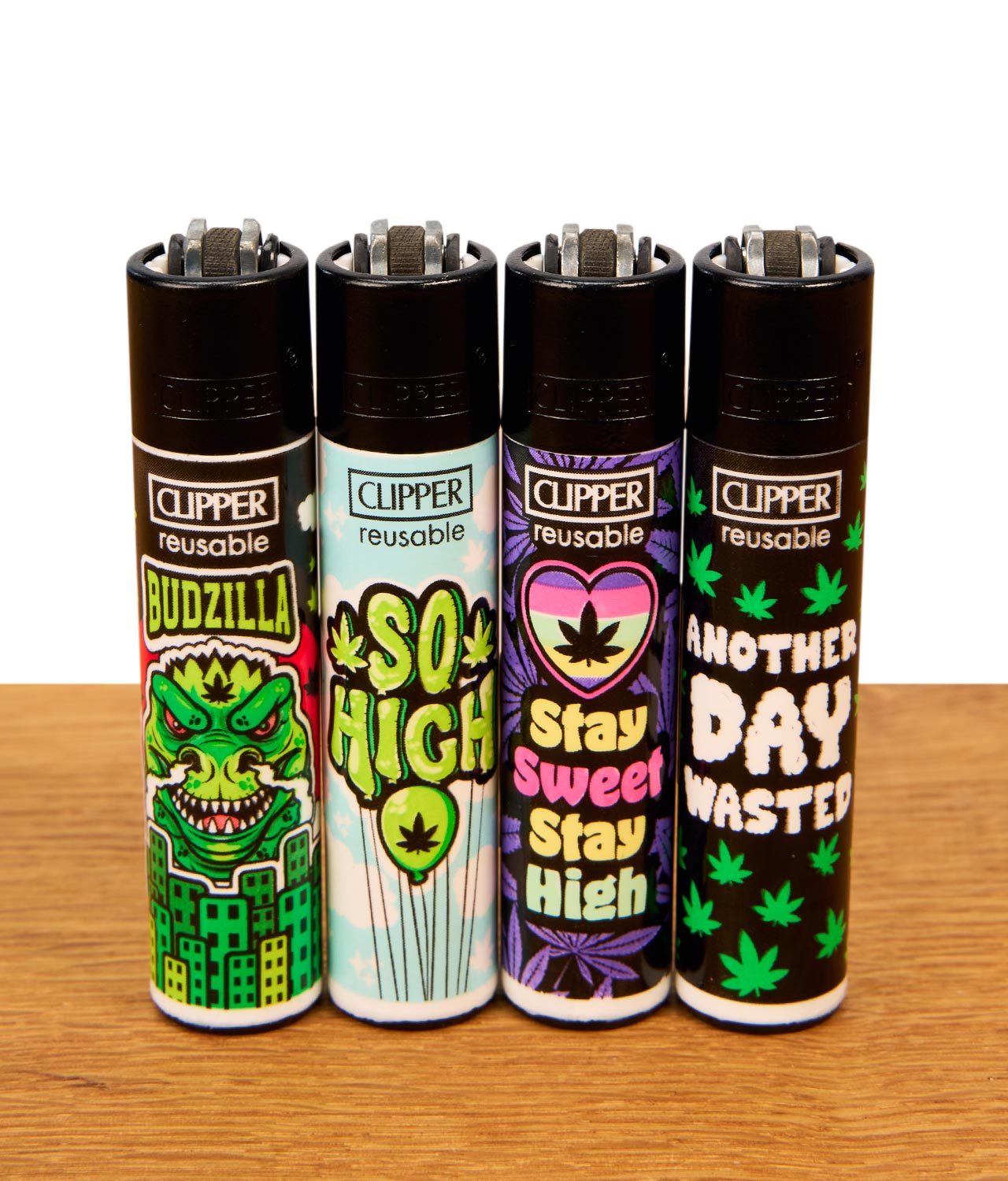 clipper-feuerzeug-420-mix-11-4er-serie-jpg Set aus vier nachfüllbaren Clipper Feuerzeugen mit verschiedenen Cannabis-Motiven auf einer Holzoberfläche.