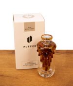 Puffco Peak Glas Save the Bees von Empire Glassworks freistehend neben der Originalverpackung. Borosilikatglas mit bernsteinfarbenem Finish.