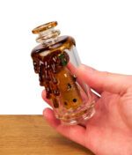 Puffco Peak Glas Save the Bees von Empire Glassworks in der Hand gehalten. Zeigt den inneren Waben-Perkolator und kleine Glasbienen.