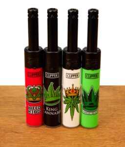 Die vollständige 4er-Kollektion der Clipper Mini Stabfeuerzeuge Canna King in den Farben Rot, Schwarz, Weiß und Grün, ordentlich nebeneinander auf einer Holzoberfläche präsentiert