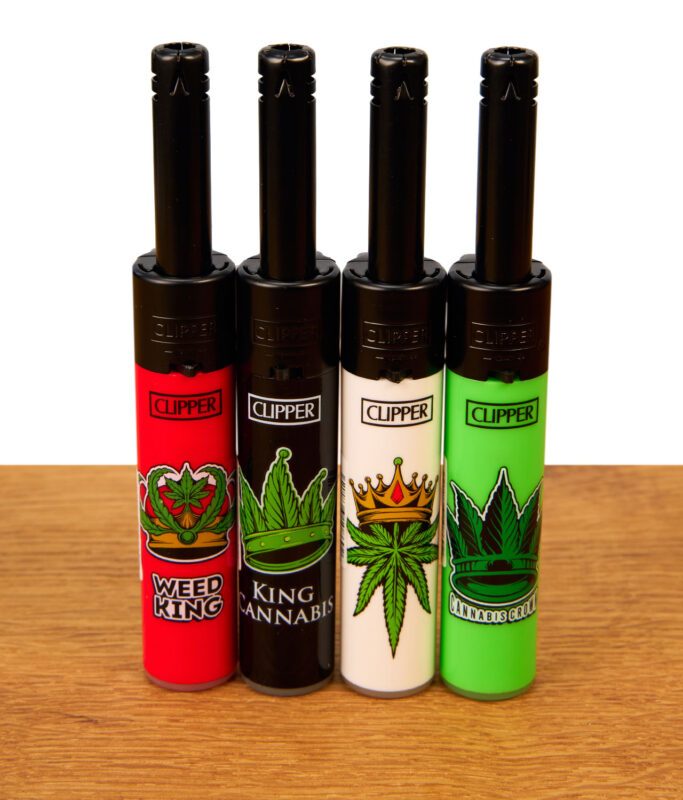 Die vollständige 4er-Kollektion der Clipper Mini Stabfeuerzeuge Canna King in den Farben Rot, Schwarz, Weiß und Grün, ordentlich nebeneinander auf einer Holzoberfläche präsentiert