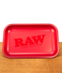 Mattrote RAW Classic Rolling Tray Drehunterlage aus Metall mit dezentem, gleichfarbigem Logo auf einer Holzunterlage.