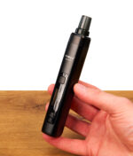 Schwarzer XMax V4 Pro Vaporizer in der Hand. Kompakter Kräutervaporizer mit mattem Gehäuse, seitlicher Airflow-Lochung und Glasmundstück.