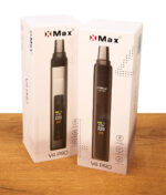 Weiße Originalverpackung des XMax V4 Pro Vaporizers auf Holztisch. Zwei Kartons zeigen das Gerät und Features wie Konvektionsheizung.