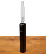 Schwarzer XMax V3 Pro Vaporizer mit montiertem Glass Bubbler. Setup mit transparentem Wasserfilter-Aufsatz stehend auf Holztisch.