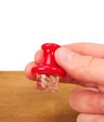 Nahaufnahme eines Nutzers, der eine rote Spinner Cap für das Dabbing hält, um die präzisen Kanäle zur Rotation von Terp Pearls zu zeigen.