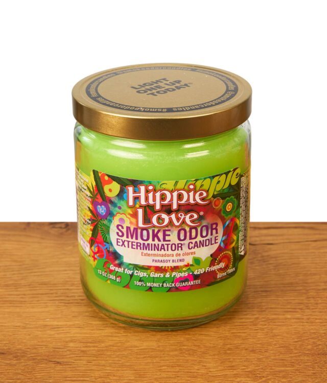 Geschlossene Smoke Odor Exterminator Duftkerze Hippie Love im großen Glas mit farbenfrohem Retro-Etikett und goldenem Schraubdeckel auf einer Holzoberfläche.