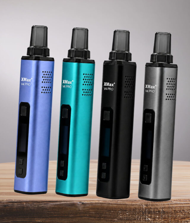 Alle vier Farben "Very Peri", "Blau", Schwarz" und "Silber" des XMAX V4 Pro Vaporizers nebendeinander auf Holz