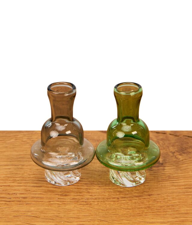 Die zwei Spinner Carb Caps für Quarzbanger in Grau & Grün stehen upright nebeneinander auf einem Holzuntergrund zur Veranschaulichung der Farbauswahl.