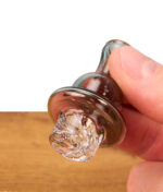 Close-up des grauen Spinner Carb Caps für Quarzbanger in der Hand; Fokus auf die spiralförmig geschwungenen Luftkanäle, die Terp Pearls im Banger rotieren lassen.