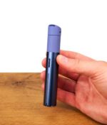 Ein saphirblauer Puffco Pivot Sapphire Vaporizer-Pen wird aufrecht in einer Hand über einer Holzoberfläche präsentiert und ist als Teil des Sapphire Bundles zu bekommen.