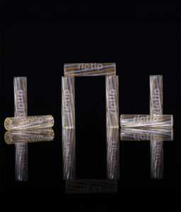 Mehrere wiederverwendbare RipTip Tangelo Glasfilter (6mm) mit ihrem charakteristischen bernsteinfarben-weißen Strudel-Design auf einer stark spiegelnden, schwarzen Oberfläche arrangiert.